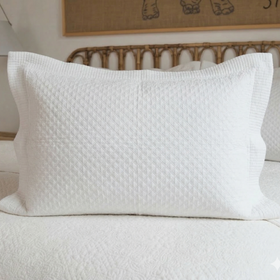 Funda de almohada blanca con textura acolchada en cama-blanco