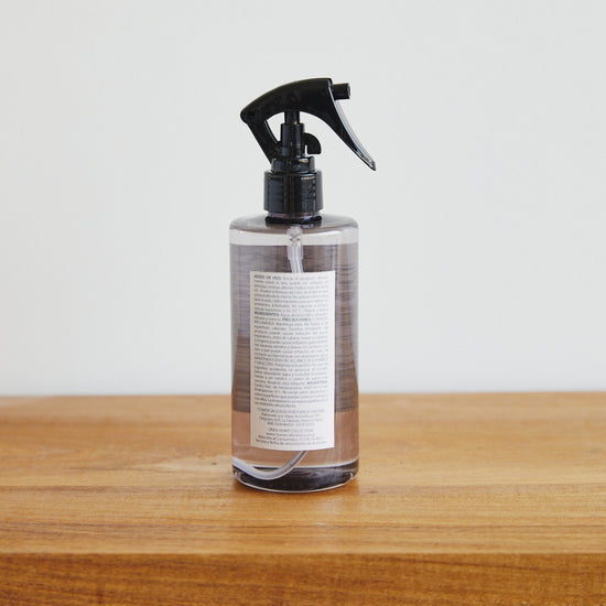Botella spray de producto textil color marrón sobre superficie de madera-peonia