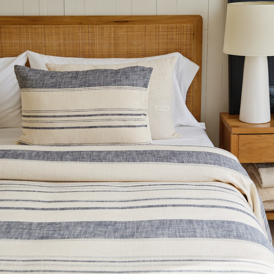 Cama con funda de edredón a rayas azules y crema con almohadas decorativas-azul