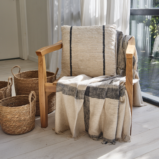 Manta Chennai gris draped sobre silla de madera en sala luminosa-gris