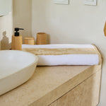 
                    
                      Toalla de playa con rayas beige sobre mueble de baño de madera-beige
                    
                  