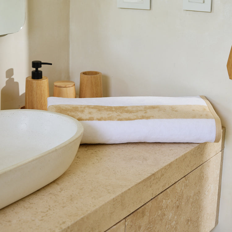 Toalla de playa con rayas beige sobre mueble de baño de madera-beige