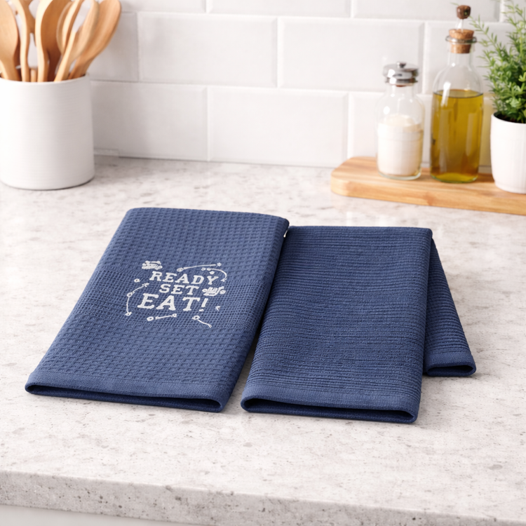 Dos repasadores azul marino con texto Ready Set Eat sobre mesada de cocina-azul