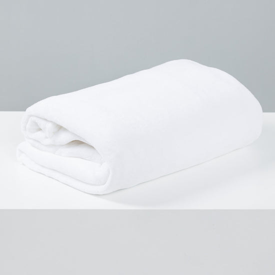 Frazada polar blanca enrollada sobre superficie gris clara-blanco