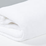 
                    
                      Frazada polar blanca enrollada sobre superficie gris clara-
                    
                  