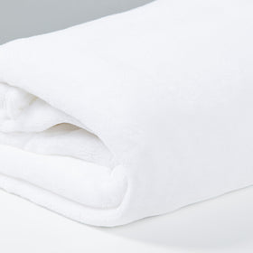Frazada polar blanca enrollada sobre superficie gris clara-