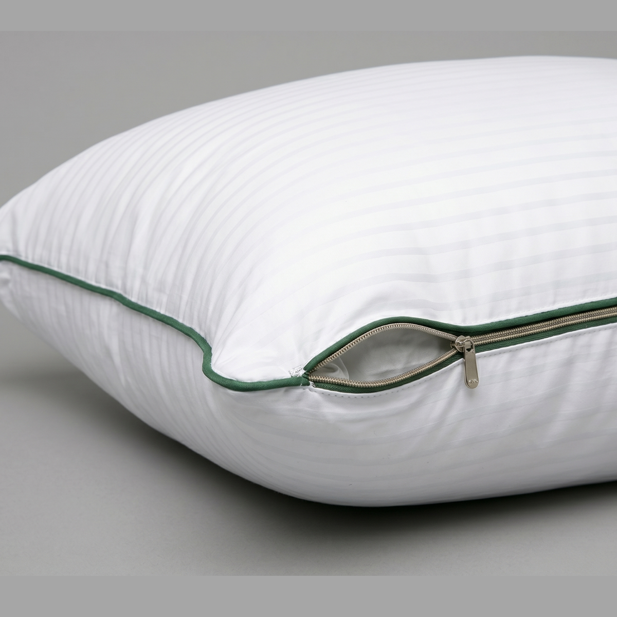 Almohada blanca con cremallera verde y ribete, vista de perfil-