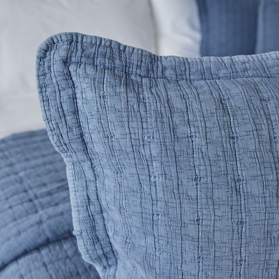 Funda de almohada azul con textura acolchada y diseño decorativo-