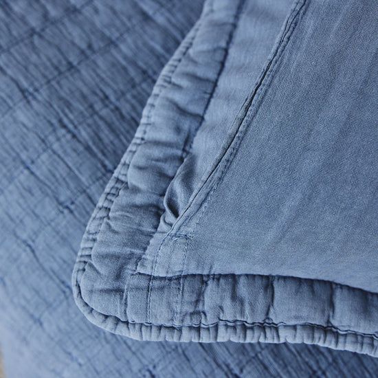 Detalle de funda almohada azul con costura y volante decorativo-