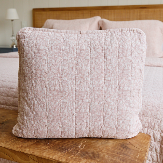 Funda de almohada Leicester 4 rosa claro sobre cama de madera-
