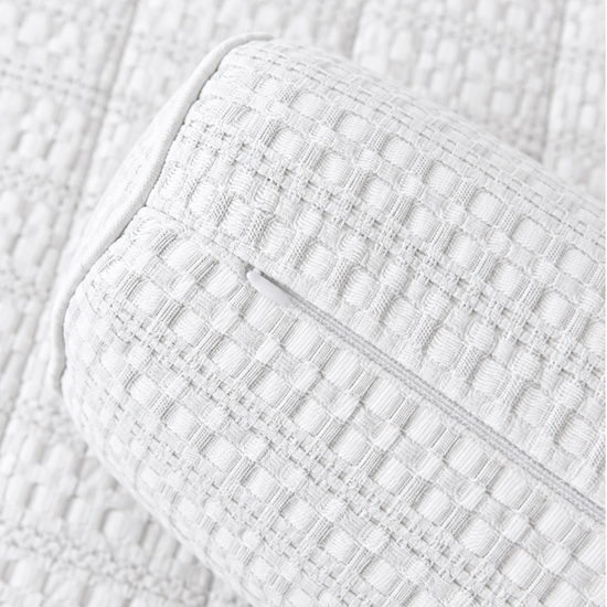 Almohada cilíndrica blanco sobre colcha acolchada de textura cuadriculada-blanco