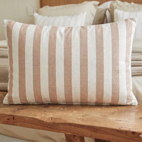 Almohada rectangular con rayas gruesas en salmón y crudo sobre banco de madera-salmón