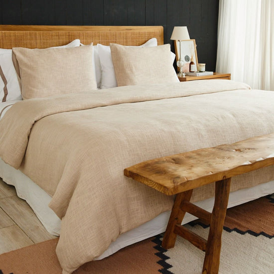 Cama con funda de edredón beige texturizado y almohadas decorativas-