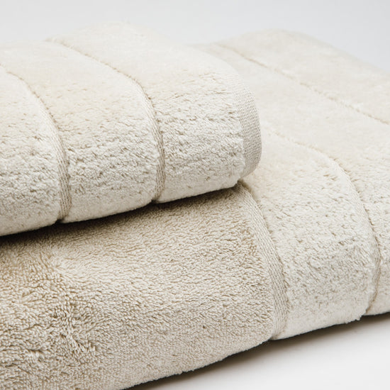 Set de toallas beige apiladas mostrando textura suave y bordes-beige