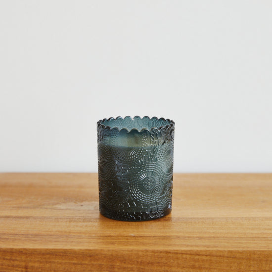Vela en vaso de vidrio verde oscuro con patrón decorativo grabado-arrayán