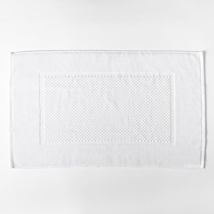 Toalla blanca rectangular con textura puntillada en el centro-