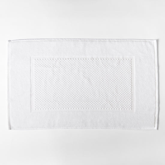 Toalla blanca rectangular con textura de puntos en el centro-