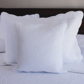 Funda de almohada blanca con patrón decorativo en cama-blanco