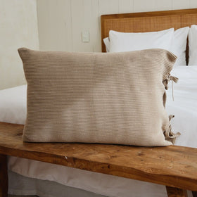 Funda almohada beige con textured en cama madera rústica-