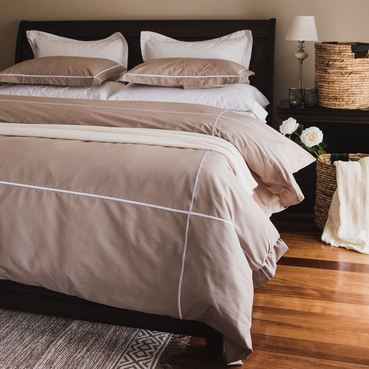 Funda edredón beige con festones y ribete blanco en cama negra-beige