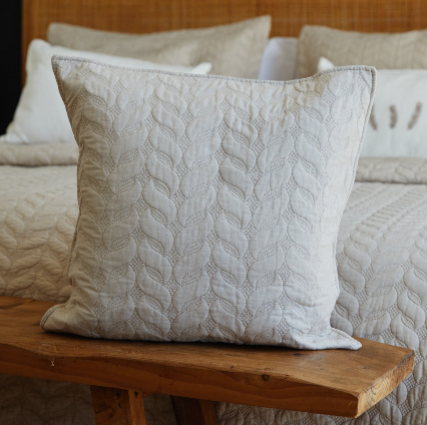 Funda de almohada blanca con textura de cable sobre banco de madera-