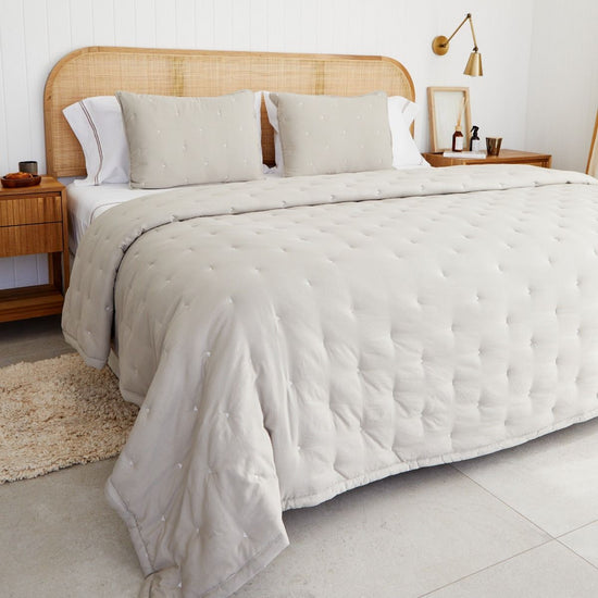 Cubrecama blanco acolchado sobre cama de ratán en dormitorio moderno-