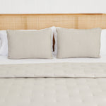 
                    
                      Cama con cubrecama acolchado beige y dos almohadas decorativas a juego-
                    
                  