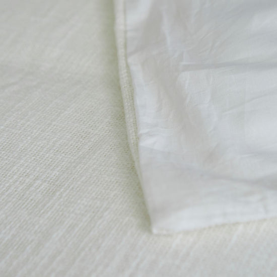 Detalle de tela blanca de funda de edredón con textura visible-