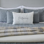 
                    
                      Cama con cubrecama gris, almohadas y cojín blanco con texto-gris
                    
                  