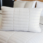 
                    
                      Almohada rectangular beige con acolchado horizontal sobre cama blanca-beige
                    
                  