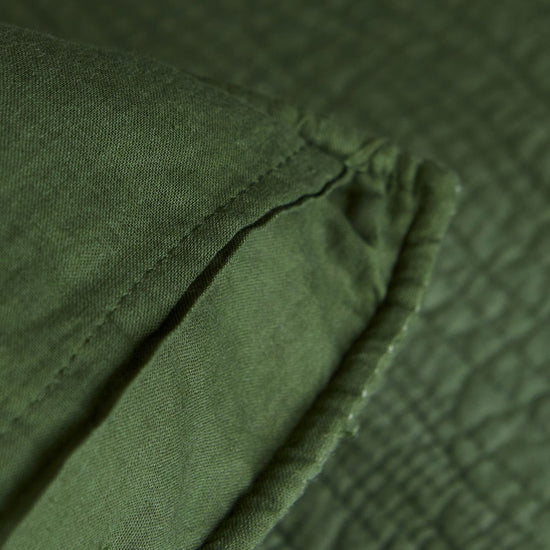 Detalle de tela verde texturizada con costuras y pliegues naturales-verde