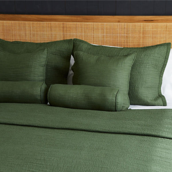 Almohada verde oscuro con textura acanalada sobre cama con sábanas verdes-verde