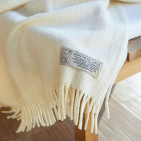 Manta de llama blanca con flecos y etiqueta de composición textil-natural