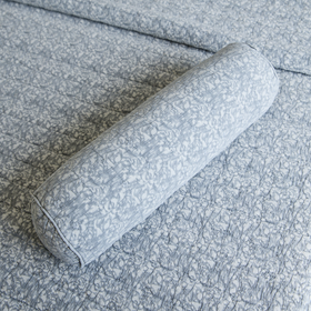 Almohada cilíndrica gris con patrón textil sobre sofá tapizado-gris