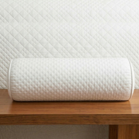 Almohada cilíndrica blanca acolchada sobre mesa de madera-blanco