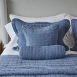 
                    
                      Cubrecama Cardiff azul con almohadas decorativas blancas en cama-
                    
                  