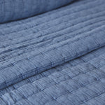 
                    
                      Detalle de textura acolchada de cubrecama azul con líneas horizontales-
                    
                  
