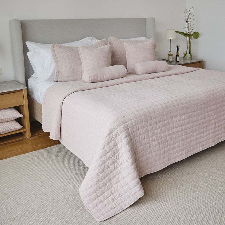 Cama con cubrecama acolchado rosa claro y almohadas decorativas-