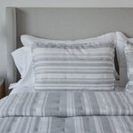 
                    
                      Cama con cubrecama y almohadas de rayas grises y blancas-
                    
                  