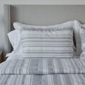 Cama con cubrecama y almohadas de rayas grises y blancas-