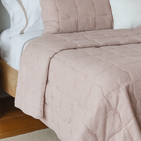 Cubrecama acolchado rosa claro sobre cama con almohadas blancas-rosa