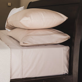 Sábana beige de algodón egipcio con dos festones apilada en cama-beige
