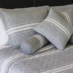 
                    
                      Almohada cilíndrica gris con franjas blancas sobre cama-gris
                    
                  