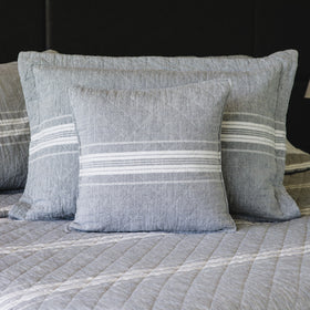 Almohada gris con rayas blancas decorativas sobre cama-gris