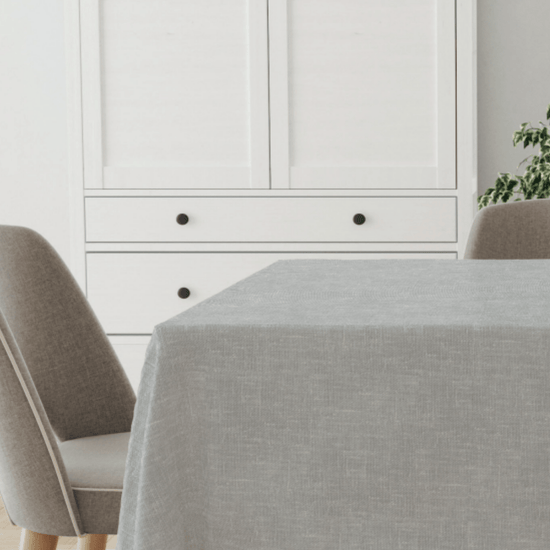 Mantel gris claro sobre mesa redonda con sillas tapizadas-gris