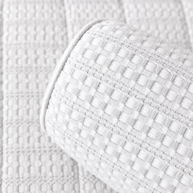 Almohada cilíndrica blanco sobre colcha acolchada de textura cuadriculada-blanco