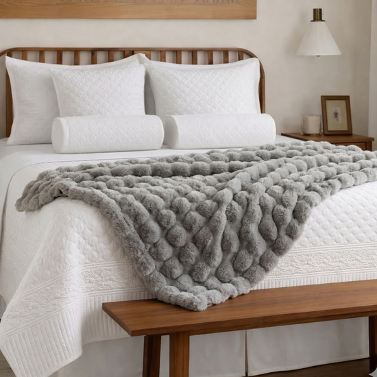 Cubrecama blanco con textura acolchada y manta gris en cama de madera-blanco