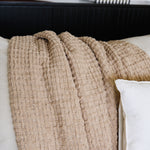 
                    
                      Manta Venecia beige texturizada sobre cama blanca-beige
                    
                  