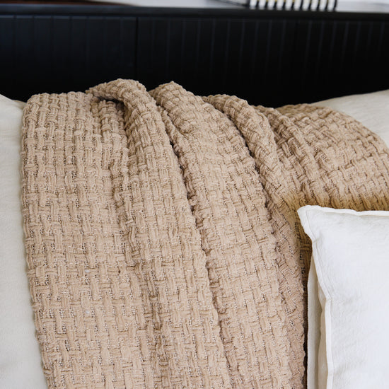 Manta Venecia beige texturizada sobre cama blanca-beige