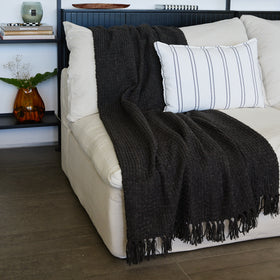 Cama blanca con manta negra y almohada rayada blanca-gris